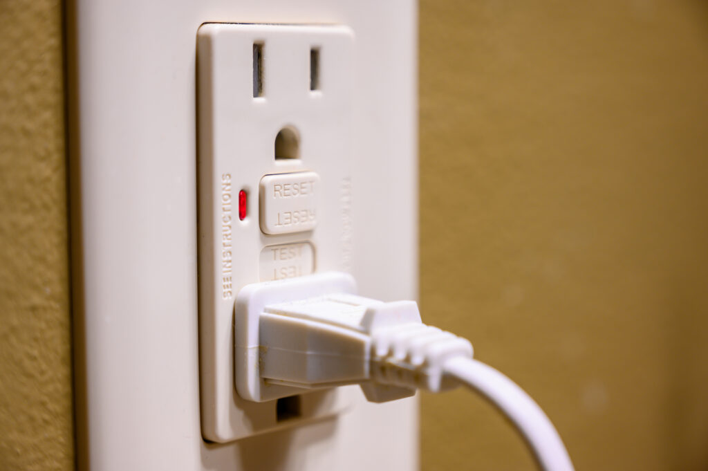 residential GFCI outlet with cord plugged in close up