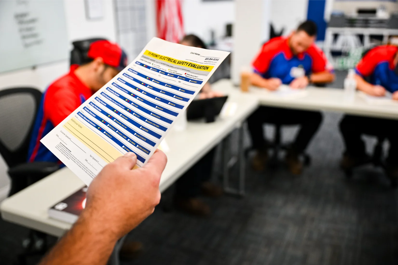 Electricians sitting in 3 red, white and blue service vans parked beside one another