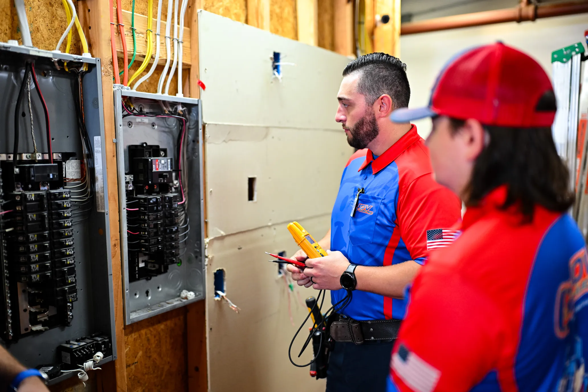 Electrician wearing safety glasses and work gloves while repairing a large electrical panel.