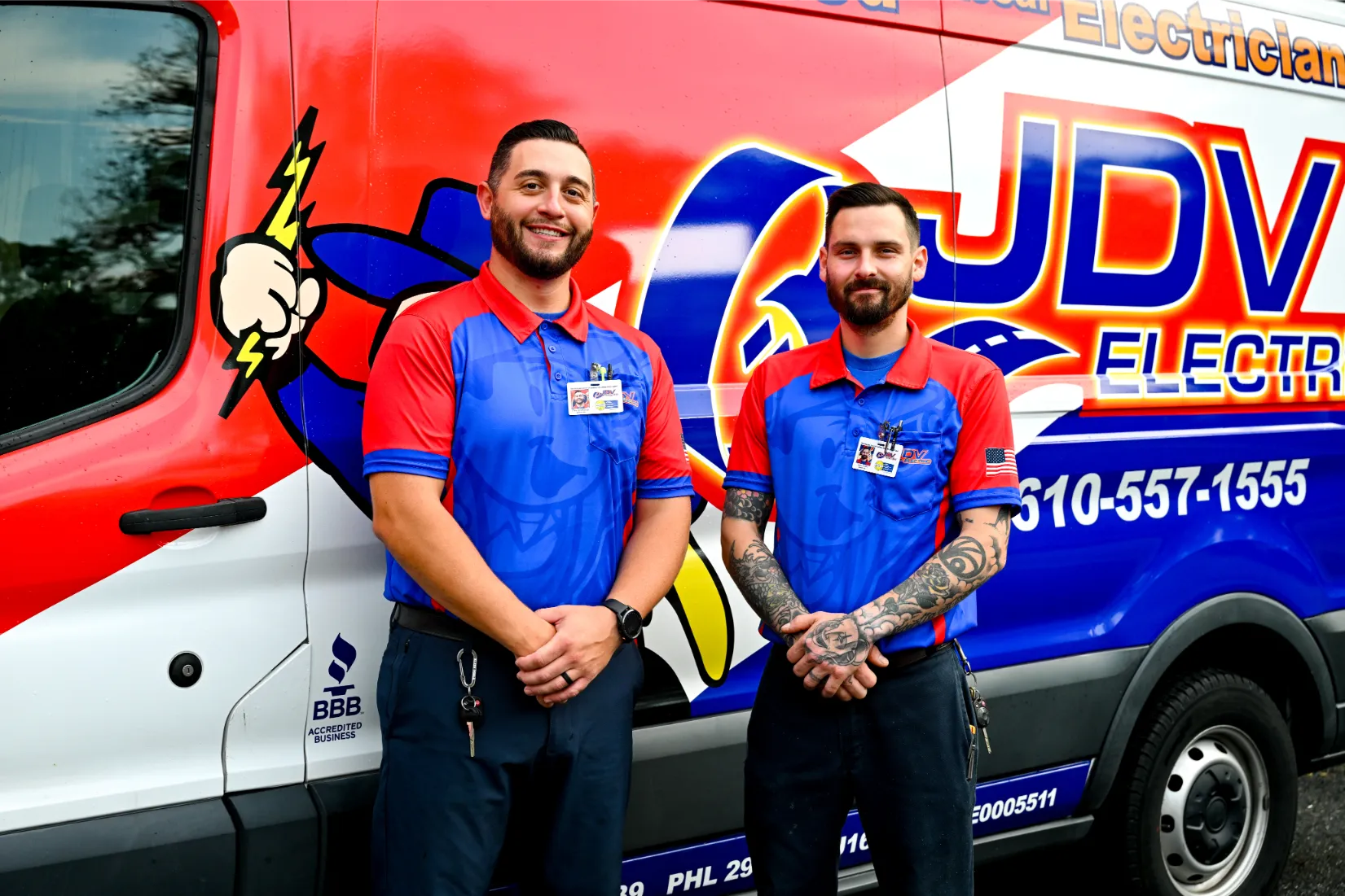 JDV Electric row of electricians in branded polos, standing together in front of a service van.