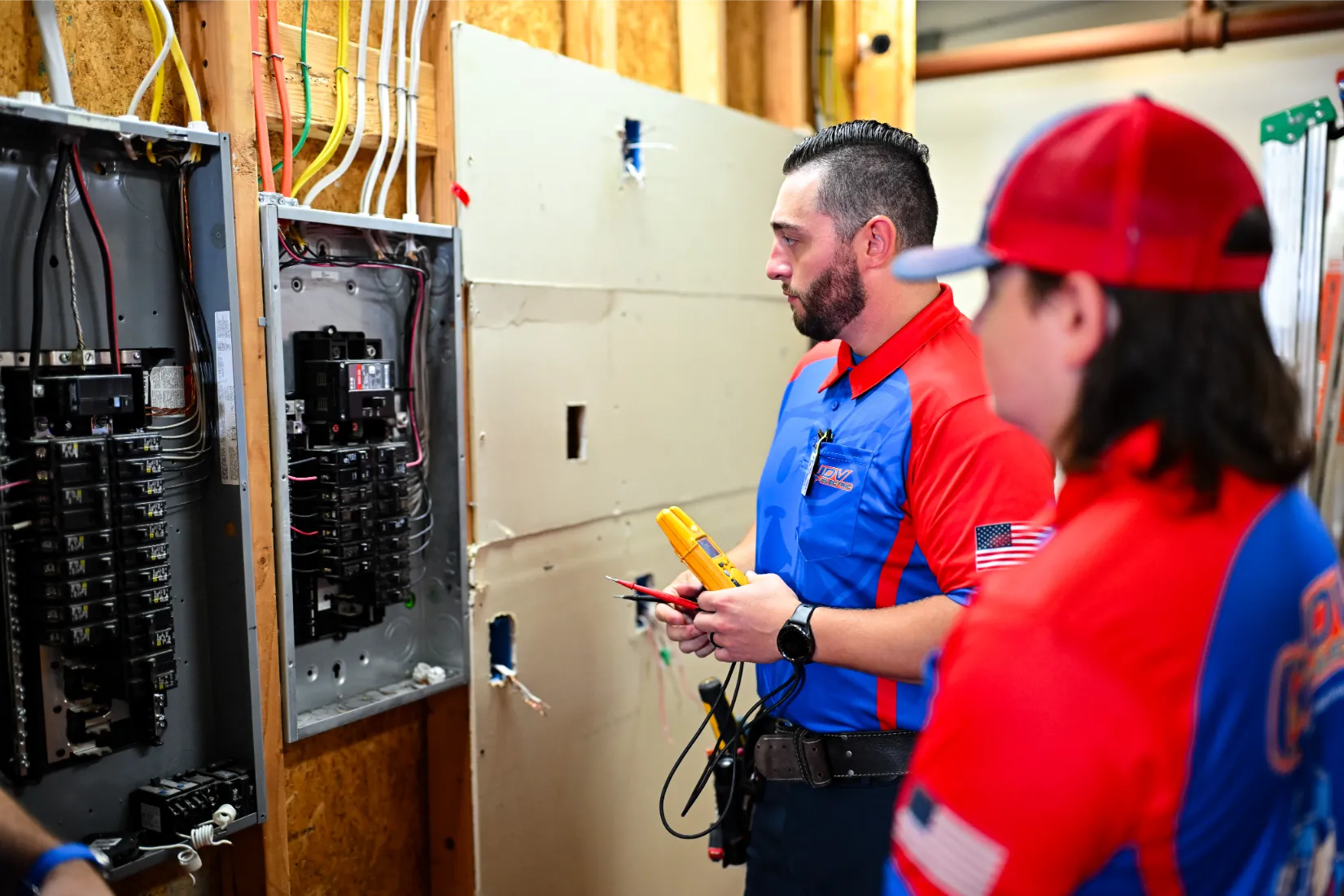 Two JDV electricians speaking in front of an electrical panel.