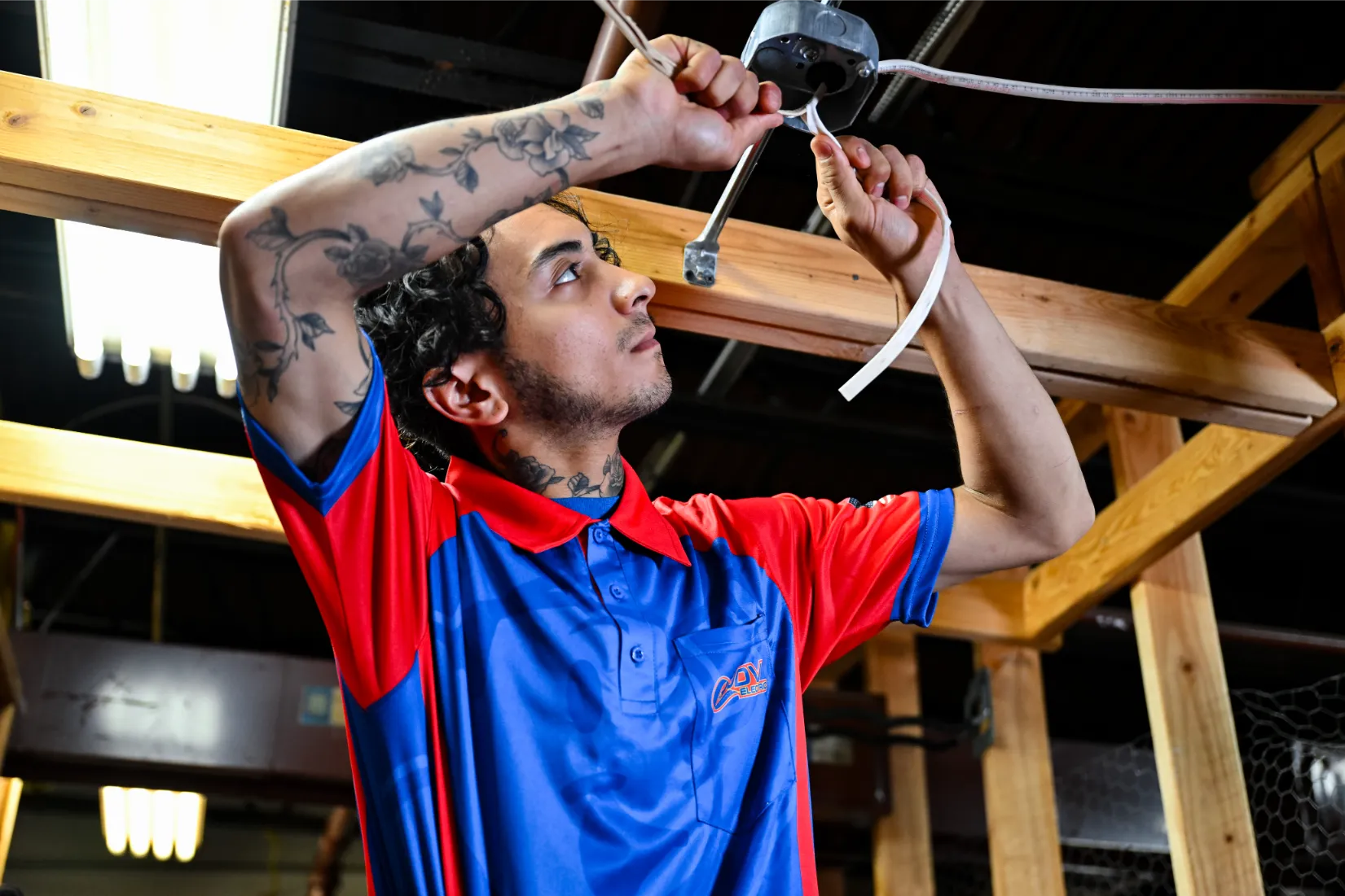 A row of JDV Electric employees standing together in front of service vans, parked in parking lot with trees in background.