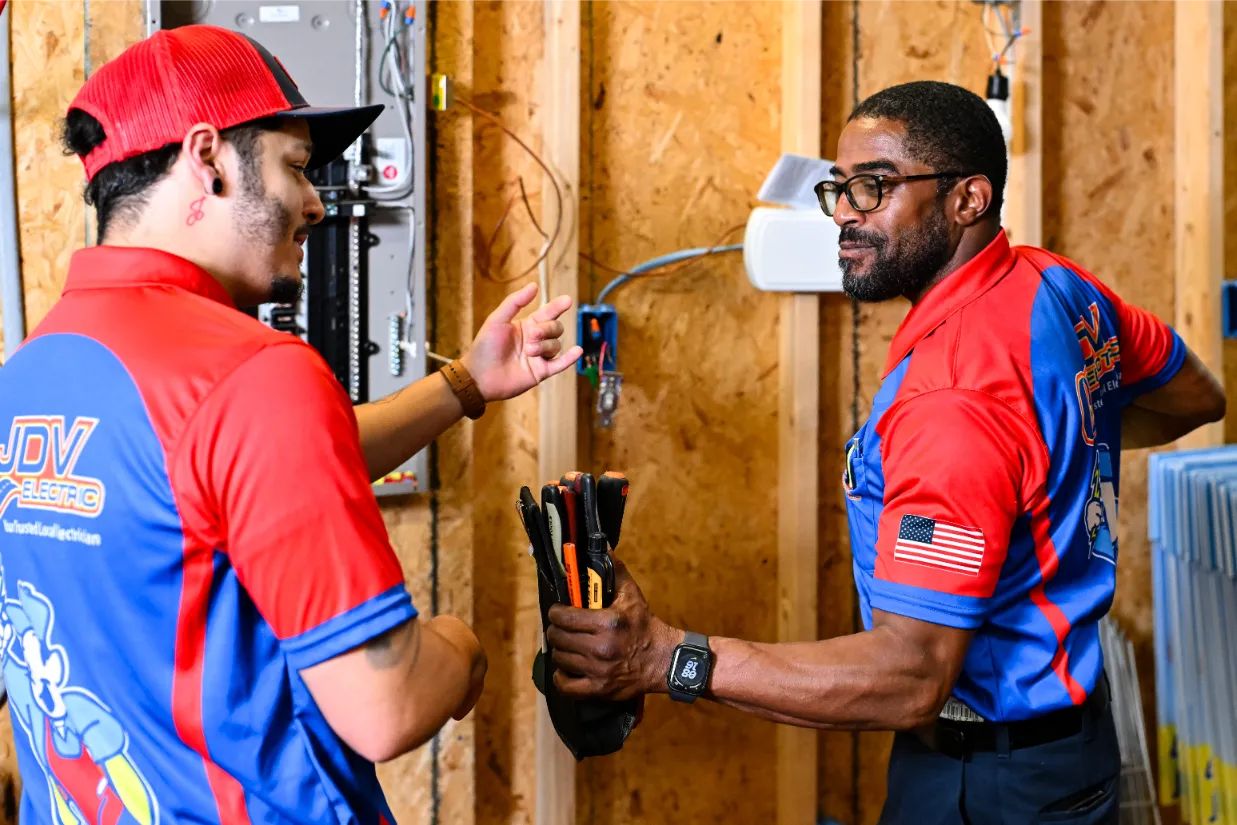 Six JDV staff members standing together in a row outside, with three service vans parked behind them.